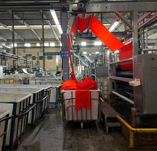 Automatic fabric spreading machine inspecting and flattening freshly dyed fabric to ensure dimensional stability before cutting.